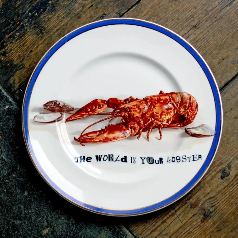 A vintage bone china plate with a lobster print. Text reads: The World Is Your Lobster.